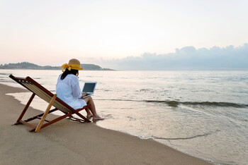Travel Trends Report - Woman using laptop at the beach.